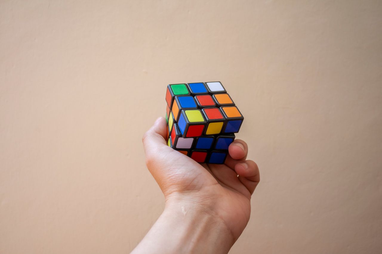 Crafting Captivating Headlines: Your awesome post title goes here Close-up of a hand holding a colorful Rubik's Cube against a neutral background.